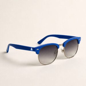 Une photo de studio montre une paire de lunettes de soleil femme de style clubmaster. La monture en acétate est d'un bleu azur vibrant, associée à un pont et des cerclages en métal argenté brillant. Les verres gris dégradé apportent une touche mystérieuse. Elles sont posées sur un fond blanc neutre et propre. Ces lunettes de soleil femme sont l'accessoire plage tendance indispensable de la collection été Marseille. Le petit logo Chouchou Beignet est visible sur la branche latérale.