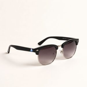 Lunettes de soleil femme au style Clubmaster tendance, avec une monture supérieure épaisse en acétate noir brillant et des branches noires. La partie inférieure de la monture est en métal argenté brillant, tout comme le pont de nez. Les verres sont dégradés, passant d'un gris foncé en haut à un gris plus clair en bas, offrant une teinte douce. La photo est prise de trois-quarts avant sur un fond blanc pur et net. Le petit logo Chouchou Beignet représentant un goéland en bouée est visible sur la branche gauche. Cet accessoire plage de la collection été Marseille est incontournable.