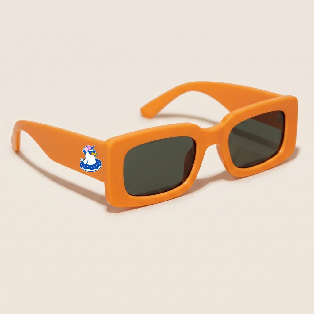 Lunettes de soleil femme tendance avec monture en plastique orange vif et forme rectangle, verres gris foncé, posées sur fond clair minimaliste, logo Chouchou Beignet sur la branche, accessoire plage de la collection été Marseille.