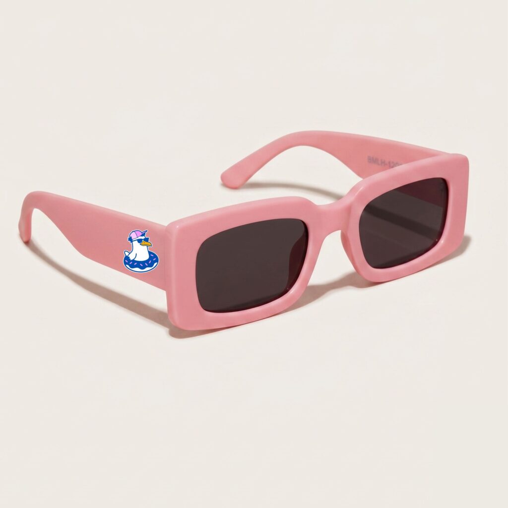 Lunettes de soleil femme tendance avec monture en plastique rose bonbon et forme rectangle, verres gris foncé, posées sur fond clair minimaliste, logo Chouchou Beignet sur la branche, accessoire plage de la collection été Marseille.