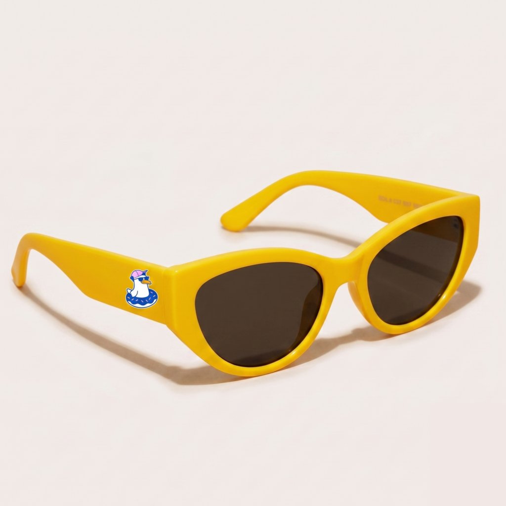 Lunettes de soleil femme tendance avec monture en plastique jaune soleil et forme cat-eye, verres gris foncé, posées sur fond clair minimaliste, logo Chouchou Beignet sur la branche, accessoire plage de la collection été Marseille.