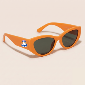 Lunettes de soleil femme tendance avec monture en plastique orange vif et forme cat-eye, verres gris foncé, posées sur fond clair minimaliste, logo Chouchou Beignet sur la branche, accessoire plage de la collection été Marseille.