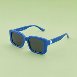 Photo lunettes de soleil modèle Droitaubut de couleur bleu azur avec le logo Chouchou Beignet sur la branche, présentées sur un fond vert éclatant, collection Chouchou Beignet Marseille.