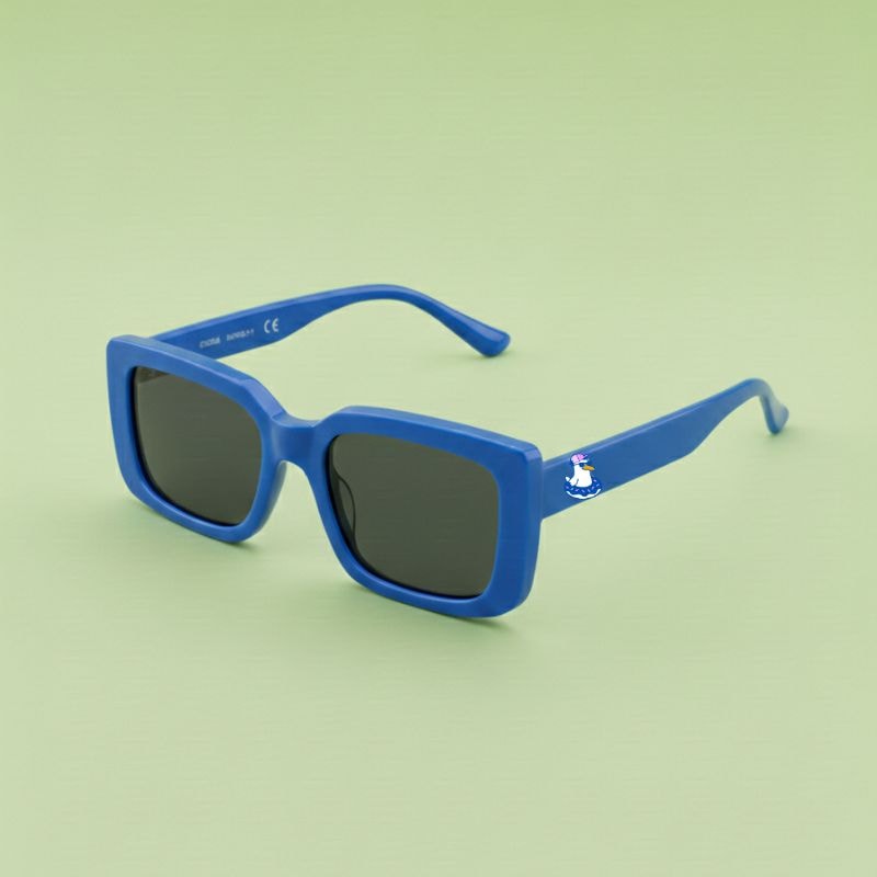 Photo lunettes de soleil modèle Droitaubut de couleur bleu azur avec le logo Chouchou Beignet sur la branche, présentées sur un fond vert éclatant, collection Chouchou Beignet Marseille.