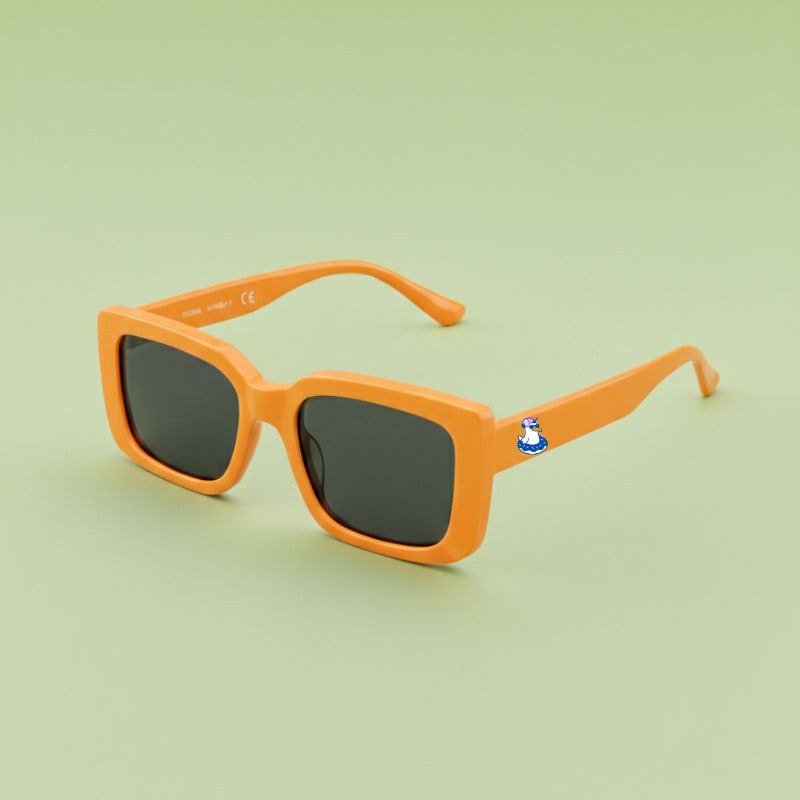 Photo lunettes de soleil modèle Droitaubut de couleur orange vif, avec le logo Chouchou Beignet gravé sur la branche, présentées sur un fond vert éclatant, collection Chouchou Beignet Marseille.