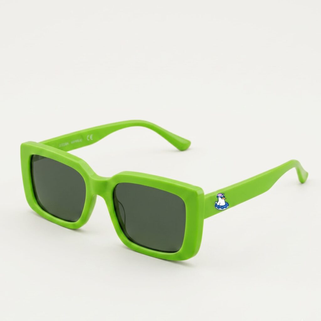 Lunettes de soleil femme tendance avec monture en plastique vert pomme et forme carrée, verres gris foncé, posées sur fond clair minimaliste, logo Chouchou Beignet sur la branche, accessoire plage de la collection été Marseille.
