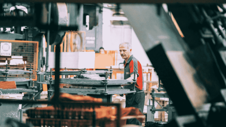Artisan opticien travaillant sur une machine de précision dans un atelier de fabrication de lunettes de soleil.