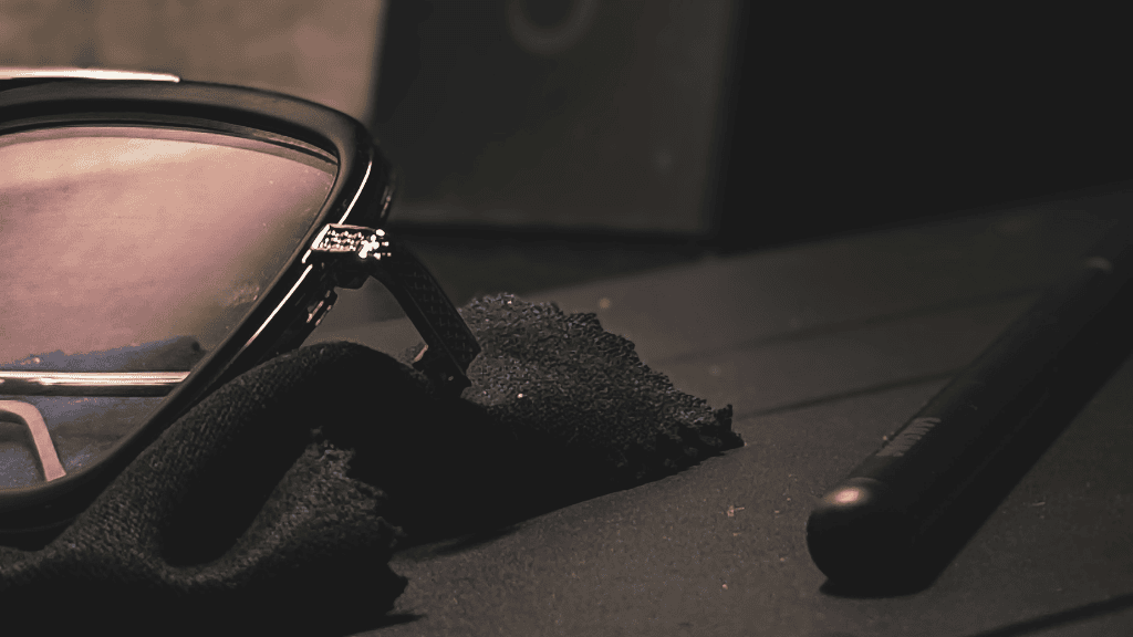 Gros plan sur une monture de lunettes de soleil haut de gamme posée sur une chiffonnette microfibre avec un stylo de nettoyage à côté.