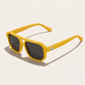 Lunettes de soleil au style aviateur revisité et tendance, se caractérisant par une monture épaisse à double pont en acétate mat de couleur jaune soleil. Les verres foncés affichent une teinte gris-noir qui protège un max. Présenté de trois-quarts face sur un fond blanc crème très épuré avec une ombre portée sur le côté, cet accessoire plage met en avant le logo Chouchou Beignet avec son gabian en bouée sur la branche gauche, une pièce maîtresse pour la collection été Marseille.