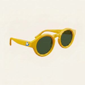 Lunettes de soleil femme tendance avec monture en plastique jaune soleil et forme ronde, verres gris foncé, posées sur fond clair minimaliste, logo Chouchou Beignet sur la branche, accessoire plage de la collection été Marseille.