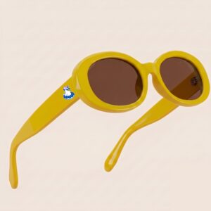 Lunettes de soleil femme tendance avec monture en plastique jaune soleil et forme ovale, verres brun teinté, posées sur fond clair minimaliste, logo Chouchou Beignet sur la branche, accessoire plage de la collection été Marseille.